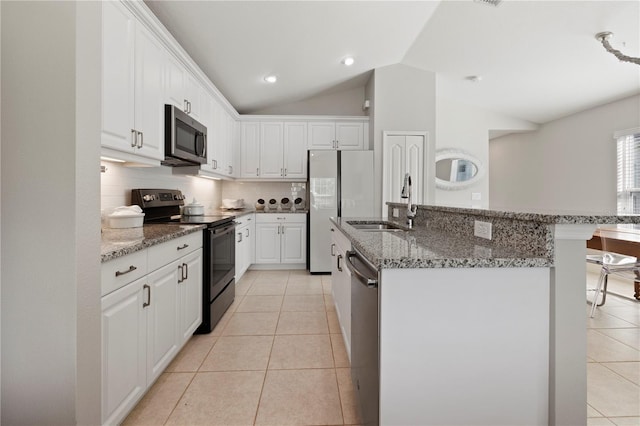 kitchen featuring sink, vaulted ceiling, light tile patterned floors, appliances with stainless steel finishes, and white cabinetry