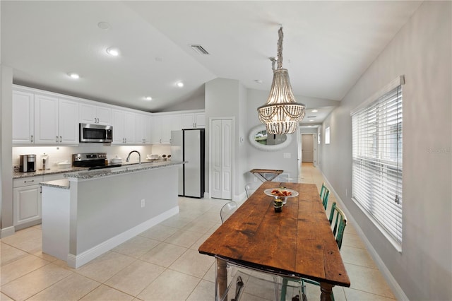 kitchen with white cabinets, light stone counters, stainless steel appliances, and vaulted ceiling