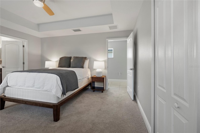 carpeted bedroom featuring a raised ceiling and ceiling fan