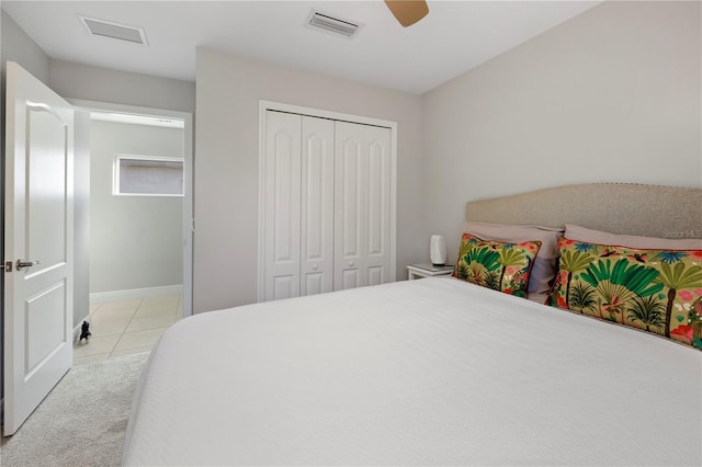 bedroom with ceiling fan, light tile patterned floors, and a closet