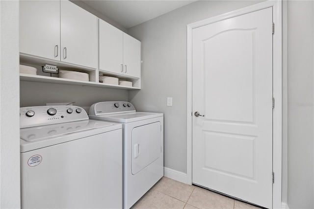 washroom featuring washing machine and clothes dryer, light tile patterned flooring, and cabinets