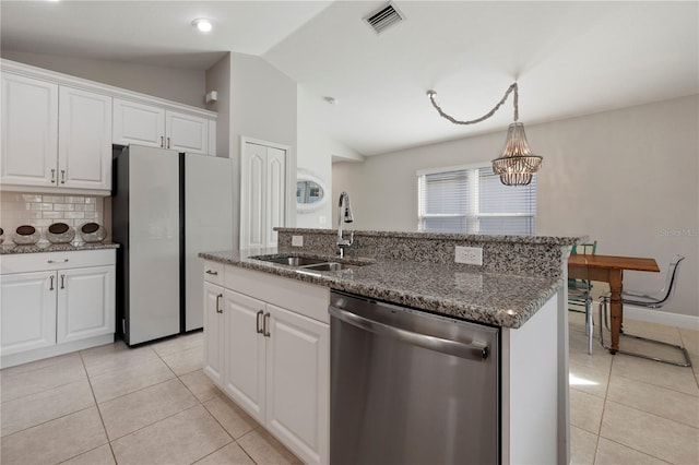 kitchen with stainless steel dishwasher, vaulted ceiling, a kitchen island with sink, sink, and white cabinetry