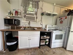 kitchen with electric stove, white cabinets, and sink