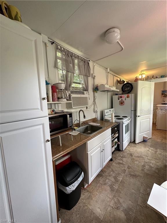 kitchen with white electric stove, sink, and white cabinets