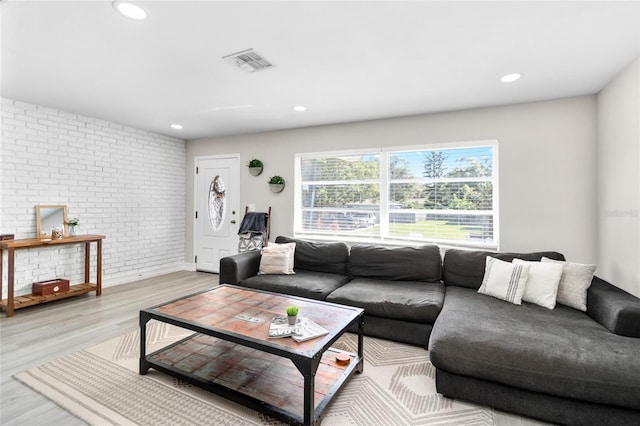 living room with light hardwood / wood-style floors and brick wall