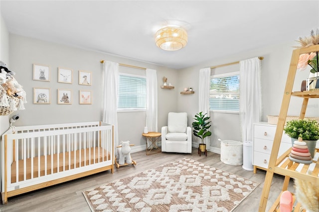 bedroom with multiple windows, wood-type flooring, and a nursery area