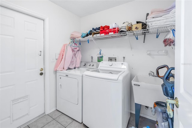 laundry room with light tile patterned flooring, washer and clothes dryer, and sink