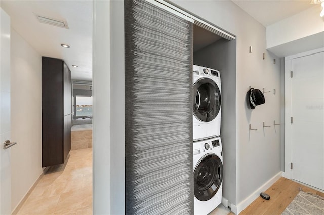 clothes washing area with stacked washer / drying machine and light wood-type flooring