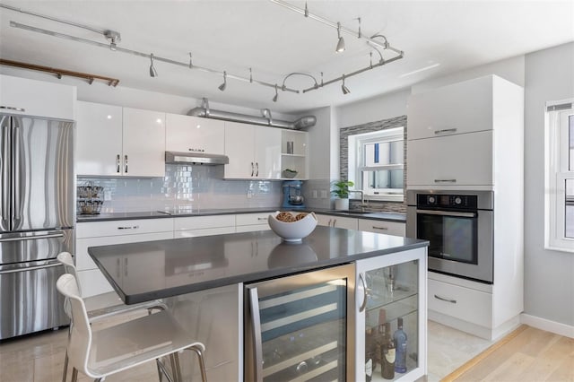 kitchen featuring backsplash, light hardwood / wood-style floors, stainless steel appliances, white cabinets, and wine cooler