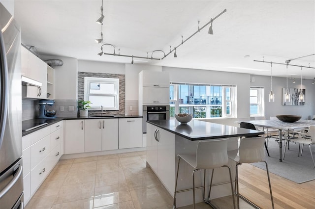 kitchen with decorative backsplash, white cabinets, stainless steel appliances, and a healthy amount of sunlight