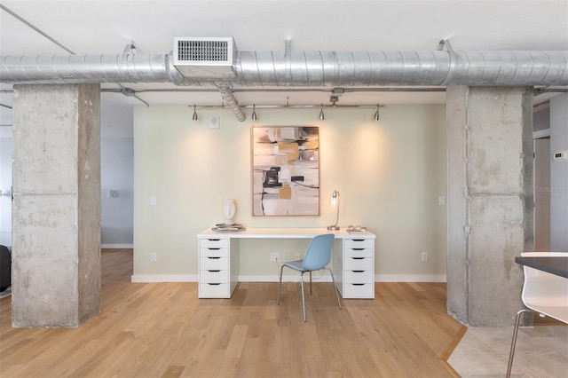 basement featuring light hardwood / wood-style flooring and built in desk