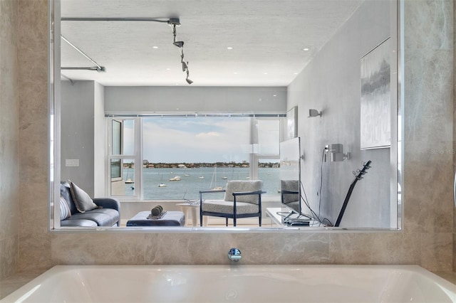 bathroom featuring a water view, a tub, and track lighting