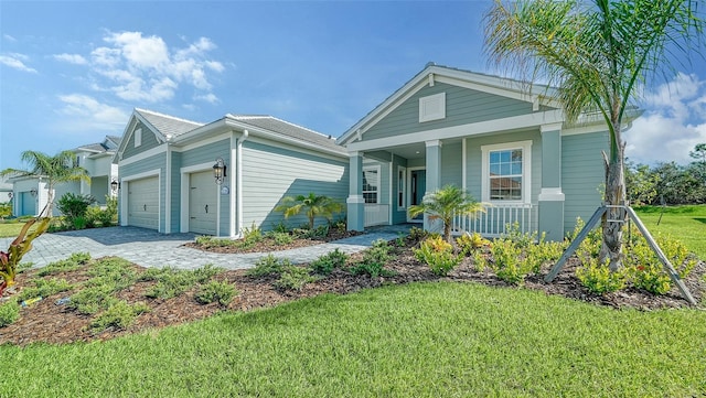 view of front of property with covered porch, a front yard, and a garage