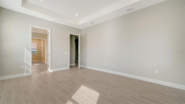 spare room with light wood-type flooring and a raised ceiling