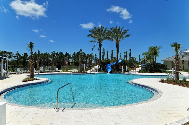 view of swimming pool with a water slide and a patio