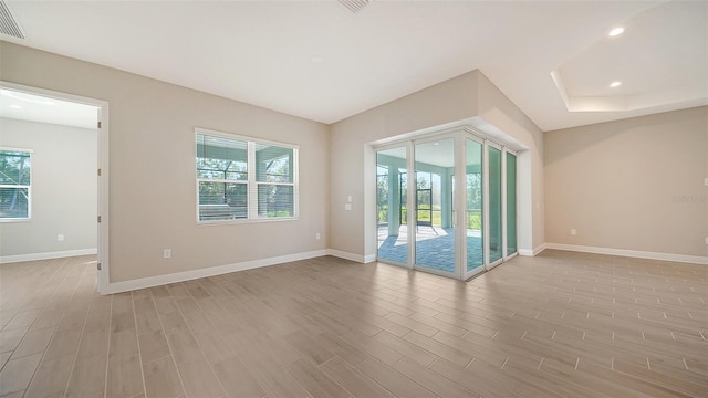 spare room with light wood-type flooring and plenty of natural light