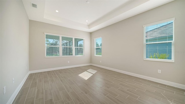 unfurnished room featuring a raised ceiling and light hardwood / wood-style floors