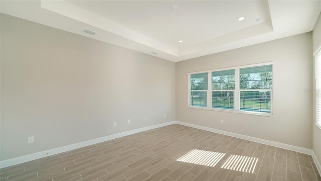 empty room featuring a raised ceiling and light hardwood / wood-style floors