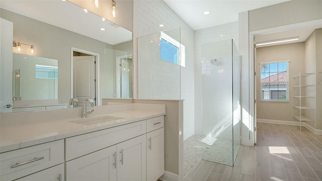 bathroom with a tile shower and vanity