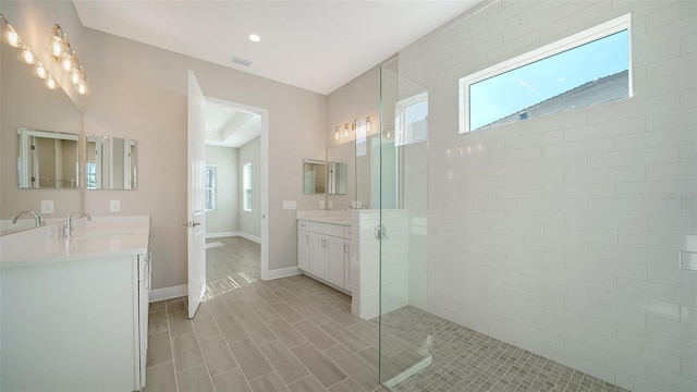 bathroom featuring plenty of natural light, tiled shower, and vanity