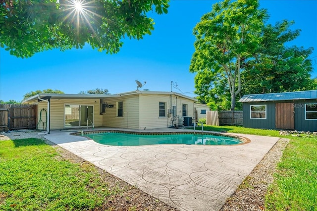 view of swimming pool with a patio, cooling unit, a lawn, and an outdoor structure