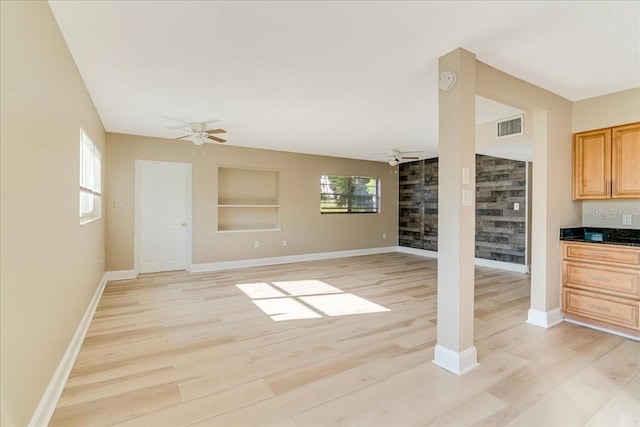 unfurnished living room with light wood-type flooring, ceiling fan, and plenty of natural light