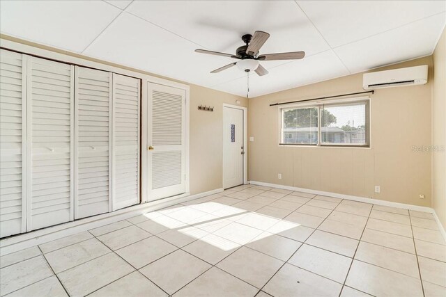 unfurnished bedroom featuring ceiling fan, light tile patterned flooring, vaulted ceiling, and a wall mounted AC