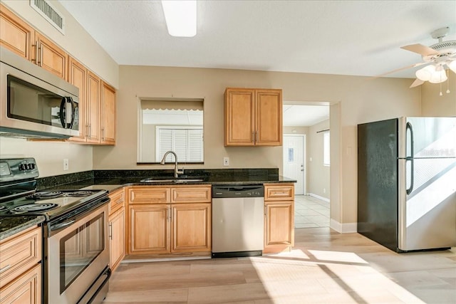 kitchen featuring appliances with stainless steel finishes, light hardwood / wood-style floors, sink, and ceiling fan