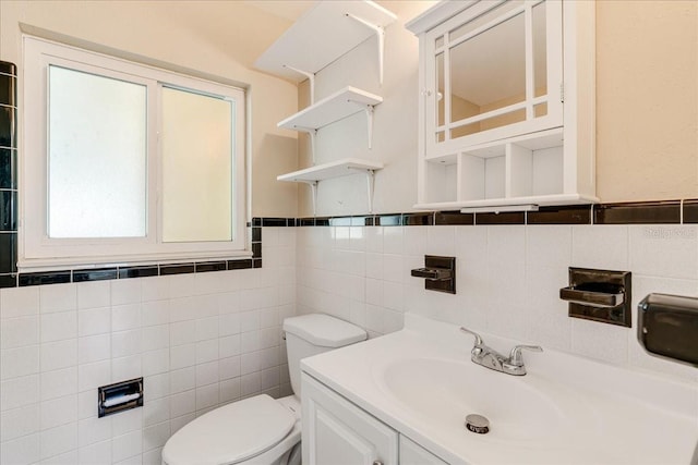 bathroom featuring tile walls, vanity, and toilet