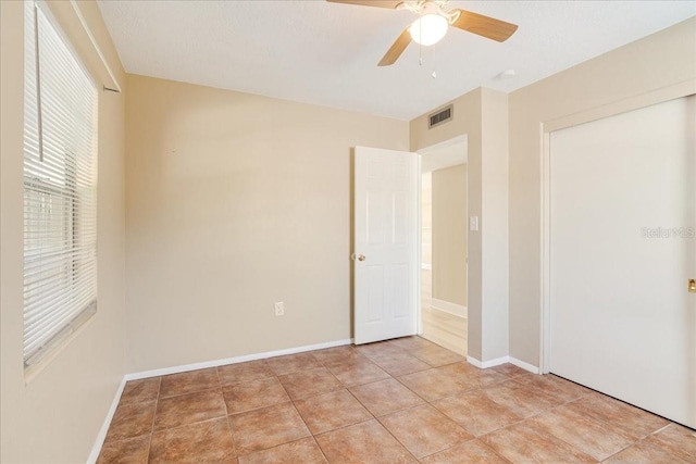 unfurnished bedroom with light tile patterned flooring, ceiling fan, and a closet