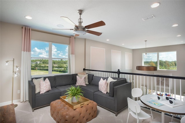 living room with light carpet, ceiling fan, and a textured ceiling