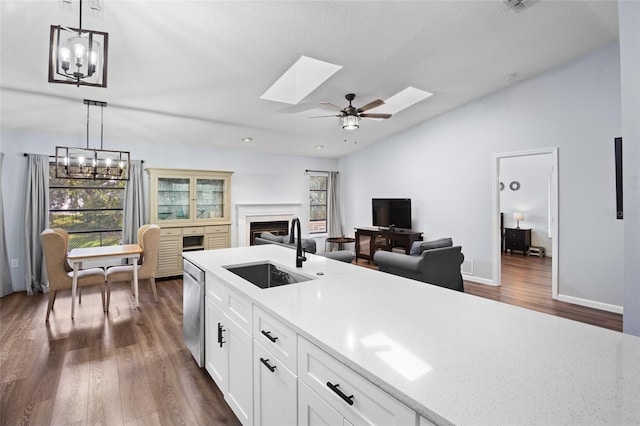 kitchen with white cabinets, hanging light fixtures, sink, dark wood-type flooring, and ceiling fan with notable chandelier