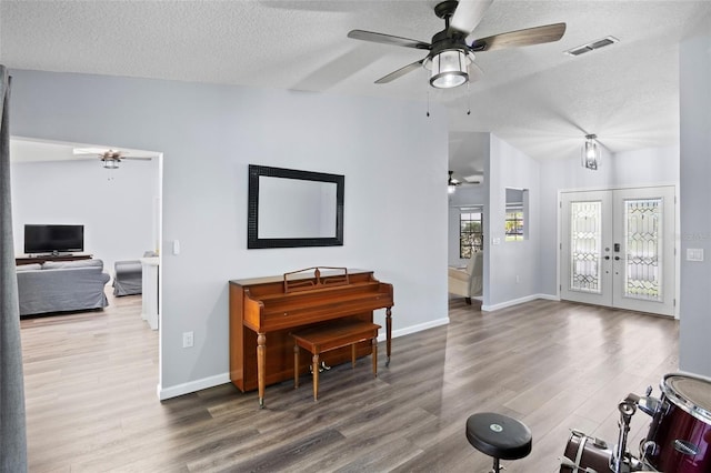 interior space featuring ceiling fan, lofted ceiling, french doors, a textured ceiling, and hardwood / wood-style floors