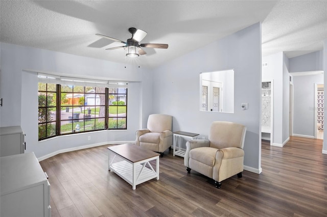 living area with ceiling fan, vaulted ceiling, a textured ceiling, and dark hardwood / wood-style flooring