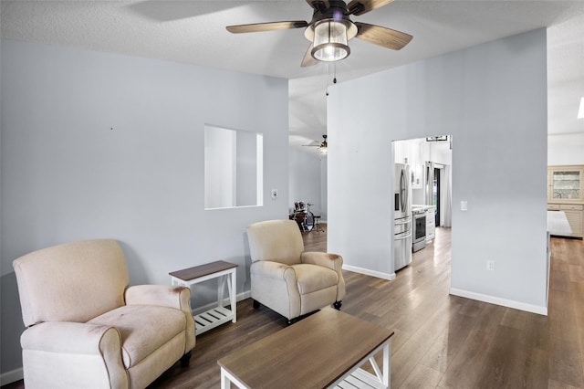 living room featuring a high ceiling, ceiling fan, dark hardwood / wood-style floors, and a textured ceiling