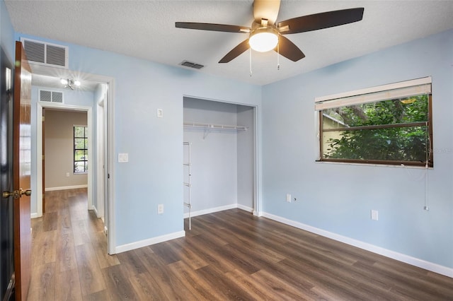 unfurnished bedroom with a closet, ceiling fan, dark hardwood / wood-style floors, and a textured ceiling