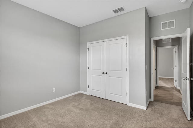 unfurnished bedroom with light colored carpet and a closet