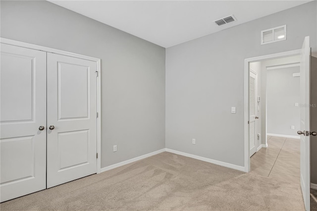 unfurnished bedroom with light colored carpet and a closet