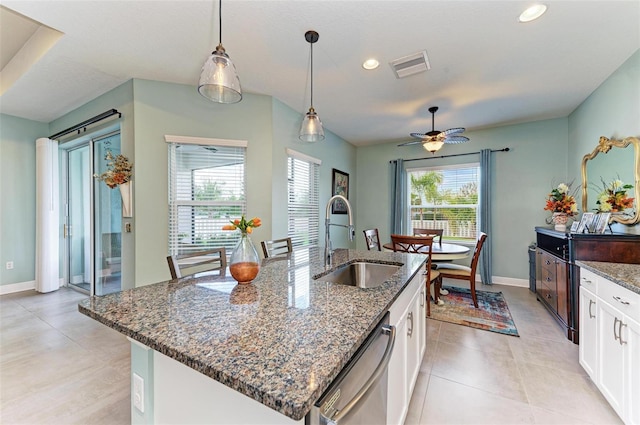 kitchen featuring white cabinets, a kitchen island with sink, sink, dark stone countertops, and dishwasher