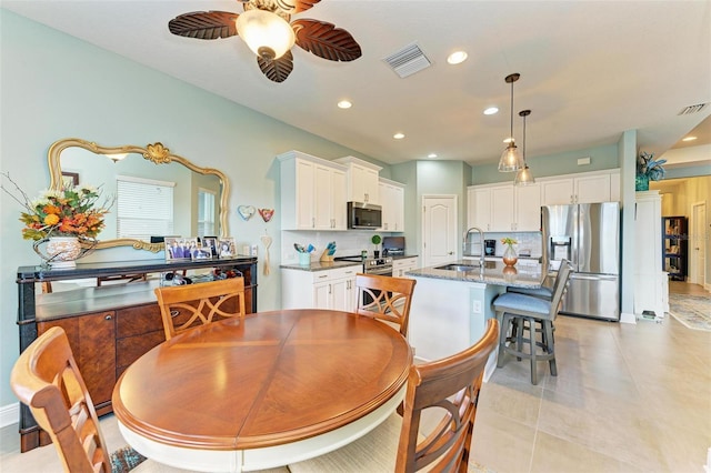 tiled dining space featuring ceiling fan and sink