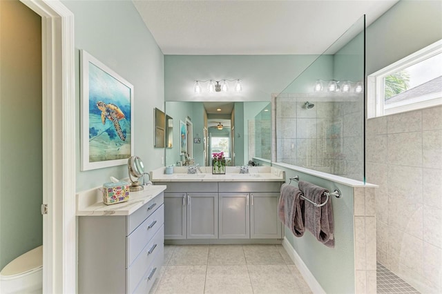 bathroom with a tile shower, tile patterned flooring, and vanity