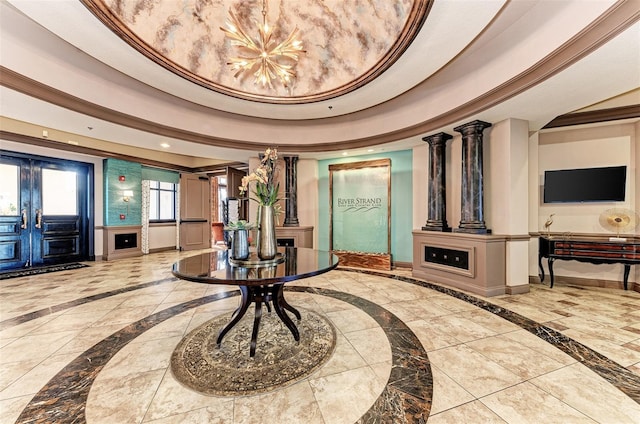 interior space featuring crown molding, a tray ceiling, french doors, and ornate columns