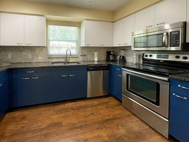 kitchen with stainless steel appliances, white cabinetry, blue cabinetry, and sink