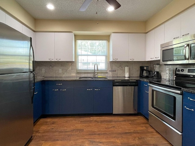 kitchen with blue cabinets, stainless steel appliances, sink, and white cabinetry