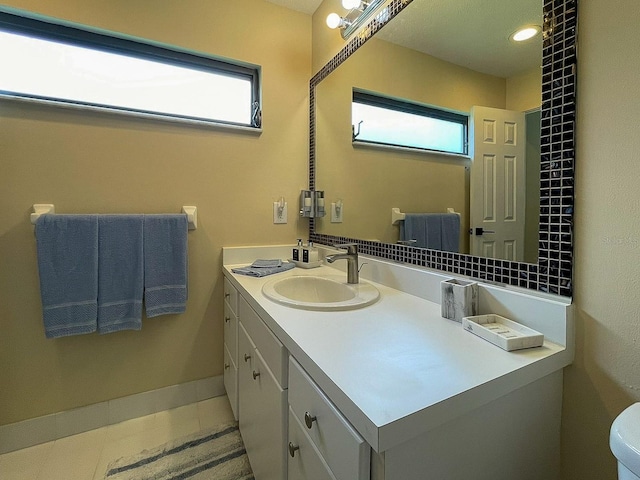 bathroom with a wealth of natural light, tile patterned floors, vanity, and toilet