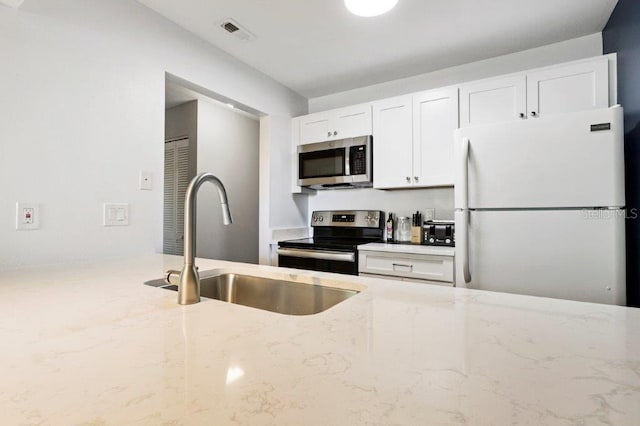 kitchen featuring light stone countertops, stainless steel appliances, sink, and white cabinets