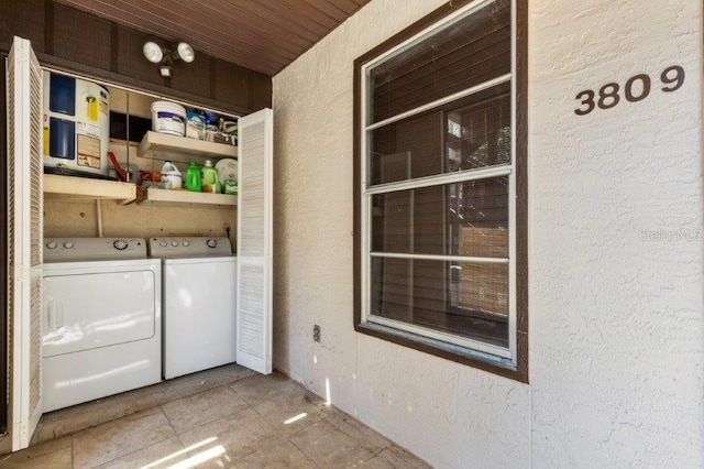 clothes washing area featuring wooden ceiling and washer and clothes dryer