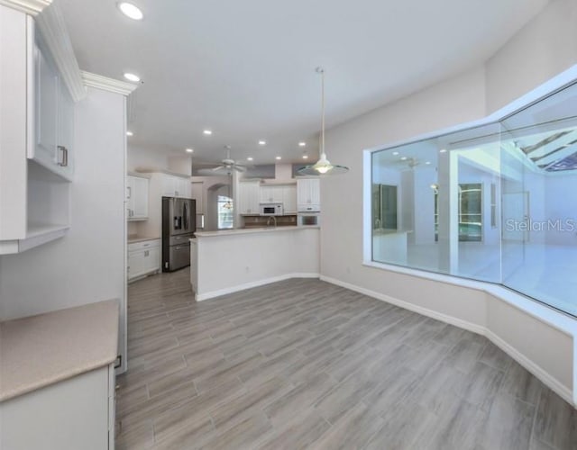 kitchen with white appliances, white cabinets, hanging light fixtures, ceiling fan, and kitchen peninsula