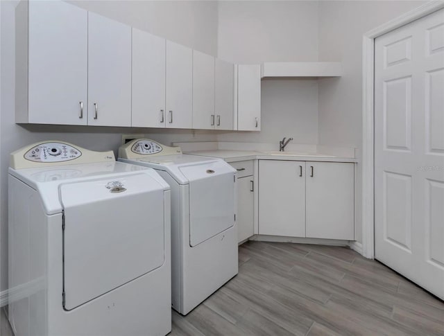 washroom featuring cabinets, separate washer and dryer, light hardwood / wood-style floors, and sink