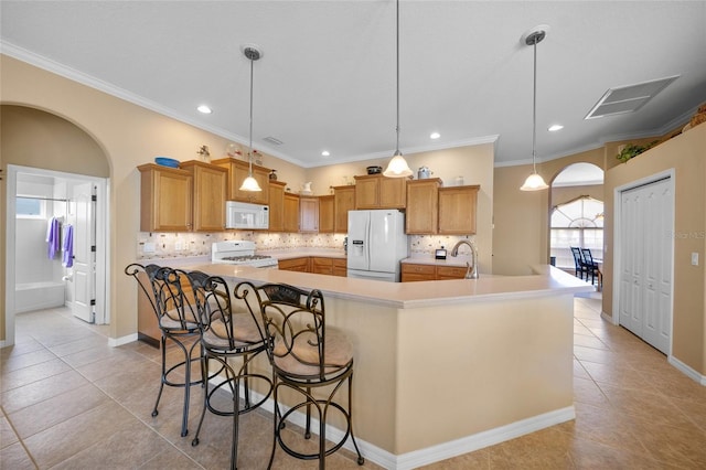 kitchen with pendant lighting, ornamental molding, white appliances, a large island with sink, and a kitchen bar